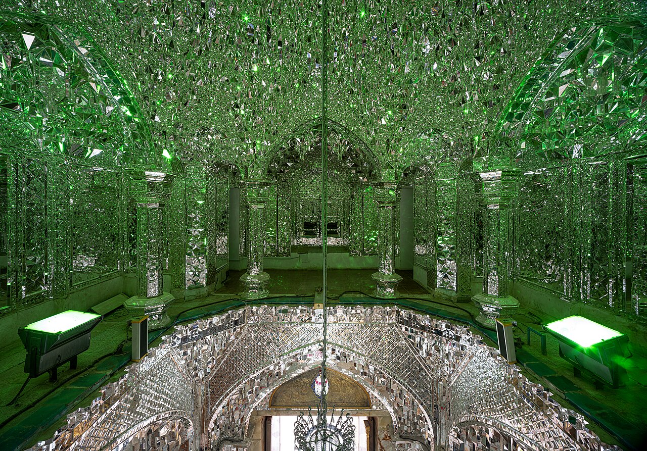 A vaulted interior densely covered with green-lit Iranian mirrorwork at the Fatima Masumeh Shrine in Qom